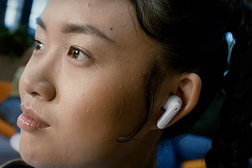 Femme portant écouteurs JBL Wave Buds blancs, écoute Bluetooth au quotidien