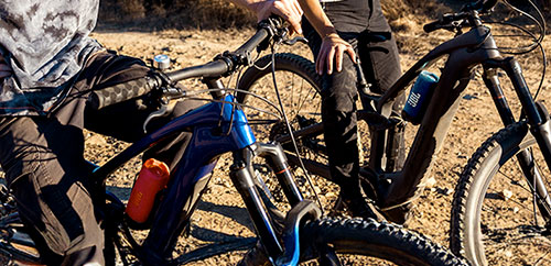 Deux cyclistes avec une enceinte JBL Flip 7 violet fixée sur un vélo en sortie tout-terrain