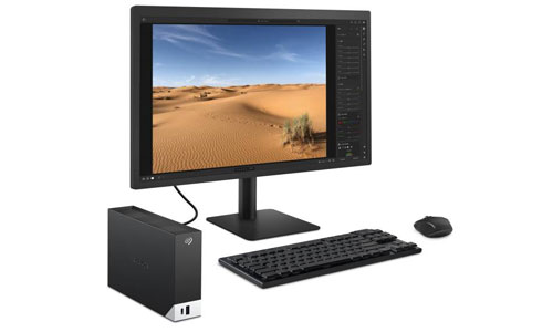 Disque dur externe Seagate One Touch Hub 16 To posé sur un bureau, avec un smartphone branché en USB pour la recharge