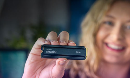 Personne tenant un SSD Crucial P510 M.2 Gen 5 devant un fond flou, sourire visible
