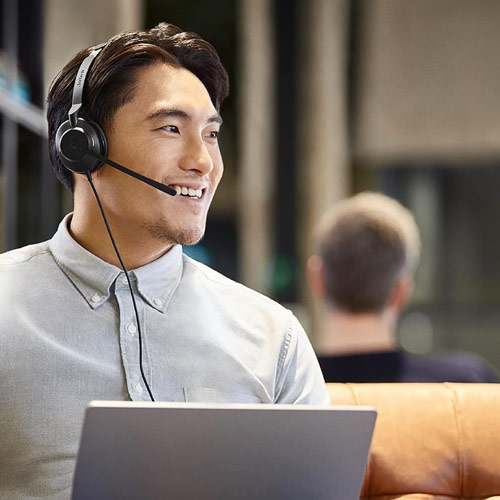 Homme portant un casque Jabra Evolve2 30 SE pendant un appel sur ordinateur portable dans un espace de travail moderne