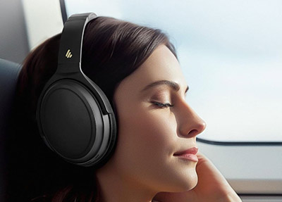 Femme portant un casque Edifier WH700NB avec suppression active du bruit dans un avion
