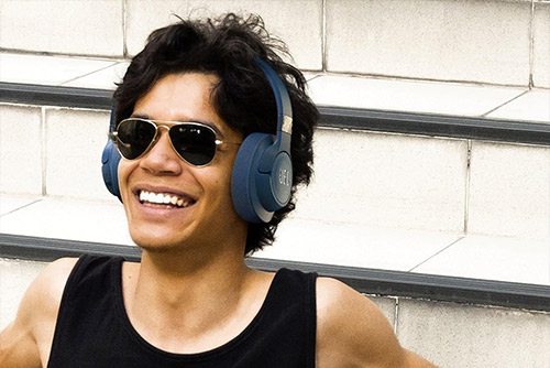 Homme souriant avec casque JBL Tune 520BT bleu, écoute Bluetooth en plein air