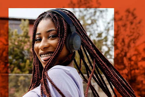 Jeune femme avec casque JBL Tune 520BT noir, écoute musicale sans fil en mouvement