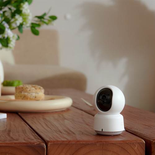 Caméra Aqara E1 posée sur une table dans un intérieur cosy