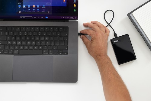 Main branchant le câble du disque dur externe My Passport sur un ordinateur portable pour lancer une sauvegarde