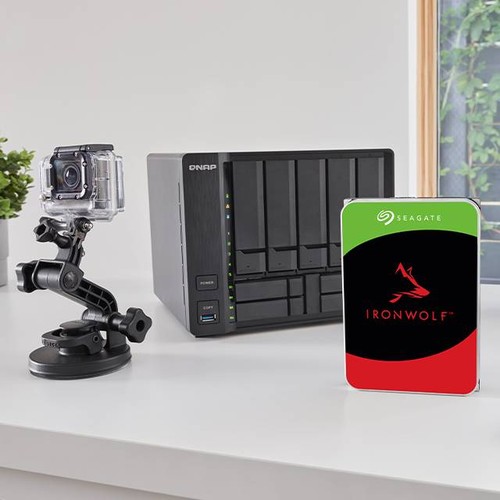 Disque Seagate IronWolf devant un NAS multibaie et une caméra